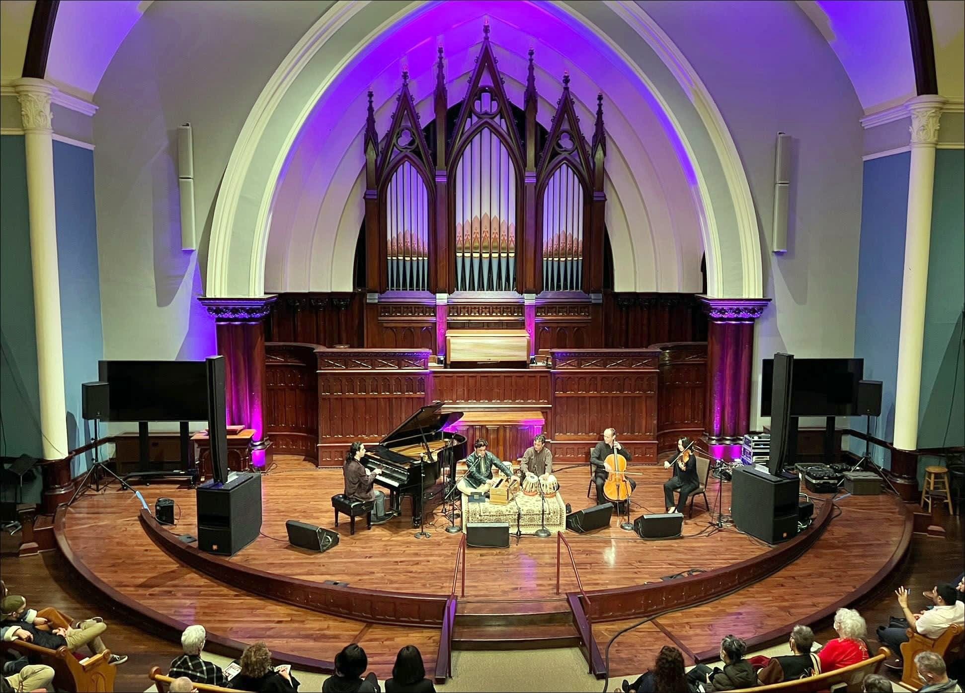 Elham Fanoos and ensemble performing in a church hall beneath a pipe organ