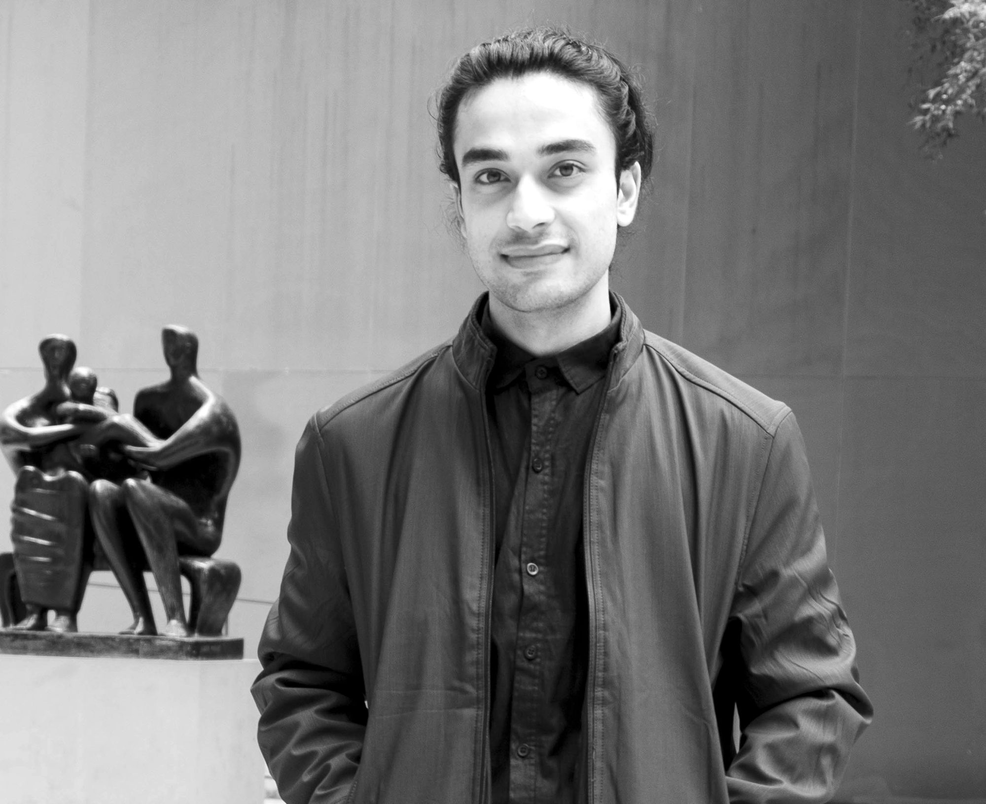 Black-and-white portrait of Elham Fanoos beside a sculpture