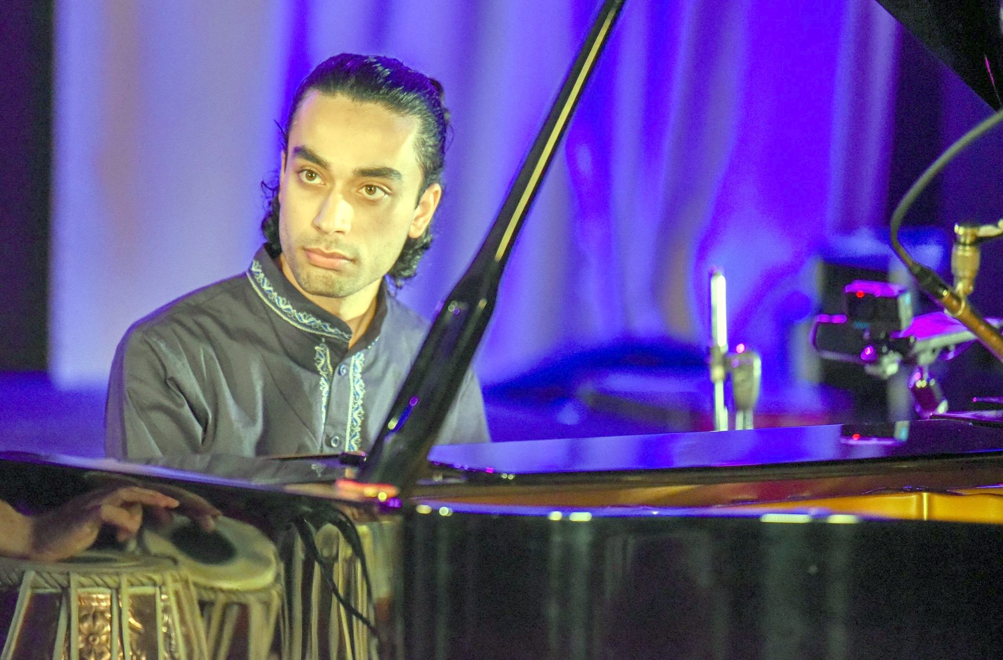 Elham Fanoos seated at the piano, looking toward the audience