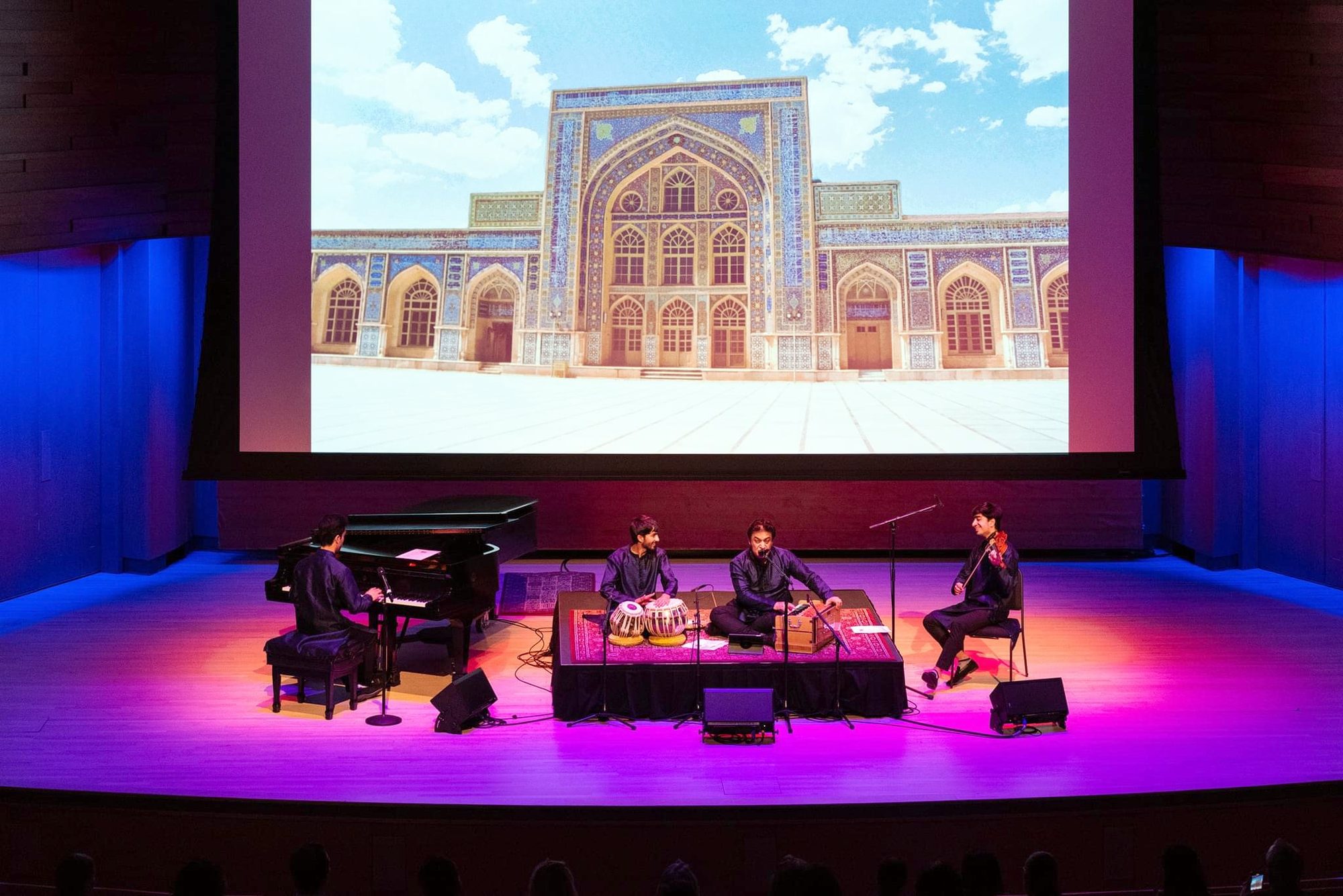 Elham Fanoos and ensemble on stage beneath a projected image of a tiled mosque façade